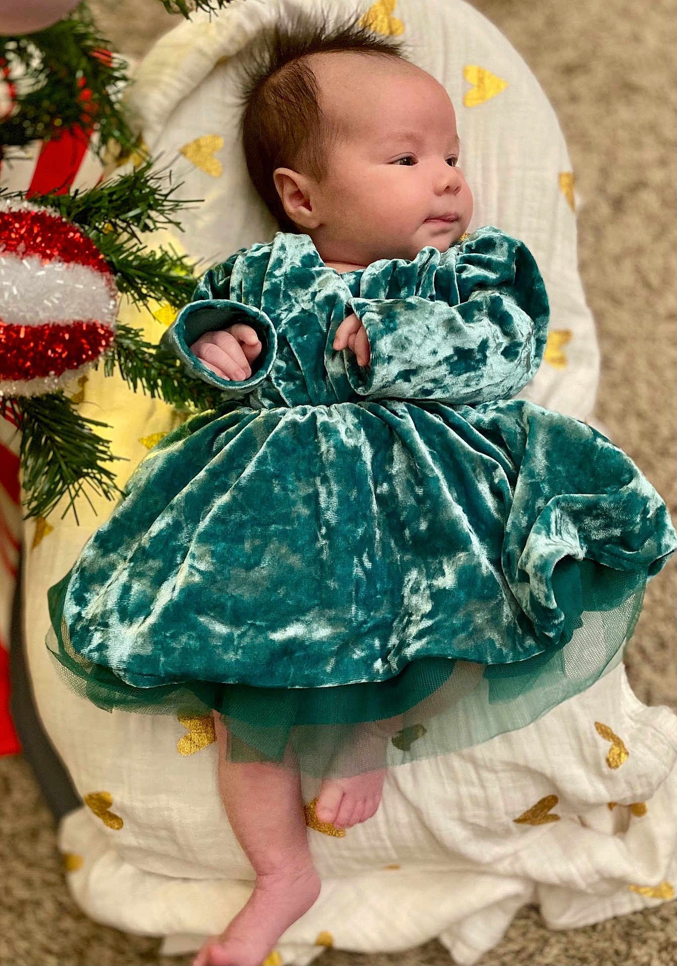 Reyna joined the competition — help win amazing prizes! baby, velvet_dress, blanket, golden_hearts, christmas_decoration, greenery, infant, foot, hand, face, curly_hair, carpet, indoors, plush, cute, holiday, decor, portrait, child, soft
