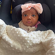 Salimata a rejoint le concours — aidez-le/la à gagner de superbes lots ! baby, infant, blanket, car_seat, headband, pink_bow, face, eyes, clothing, cute, child, person, indoors, portrait, seat, fabric, texture, cozy, expression, newborn