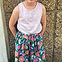 casual, child, colorful_clothing, concrete_wall, cute, earrings, fashion, flower_pattern, girl, greenery, happy, outdoor, portrait, sandals, sidewalk, sleeveless_top, smiling, standing, summer, young