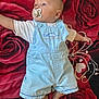 baby, blue_eyes, casual_clothing, child, cute, indoors, infant, light_blue_overalls, lying_down, pacifier, peaceful, portrait, red_blanket, relaxed, rose_pattern, short_hair, small_feet, soft_fabric, toddler, white_shirt
