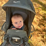 Joe joined the competition — help win amazing prizes! baby, child, face, carrier, outdoor, nature, autumn, leaves, smile, person, head, straps, forest, sunlight, happy, baby_carrier, clothing, young_child, seated, daylight