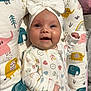 baby, infant, smile, white_bow, onesie, elephant_pattern, cushion, colorful, cute, face, child, happy, indoor, fabric, pattern, headwear, portrait, baby_girl, clothing, soft