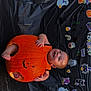 baby, pumpkin, halloween, costume, smile, face, black_background, stickers, decorations, orange, cute, holiday, child, festive, happy, sitting, celebration, indoors, joyful, hollow_pumpkin