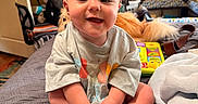 Rylei is registered to the contest to win money with this photo: baby, child, smiling, sitting, bed, bedroom, dog, golden_retriever, toy, colorful_toy, blanket, shirt, barefoot, portrait, indoors, home, furniture, happy, pet, playroom