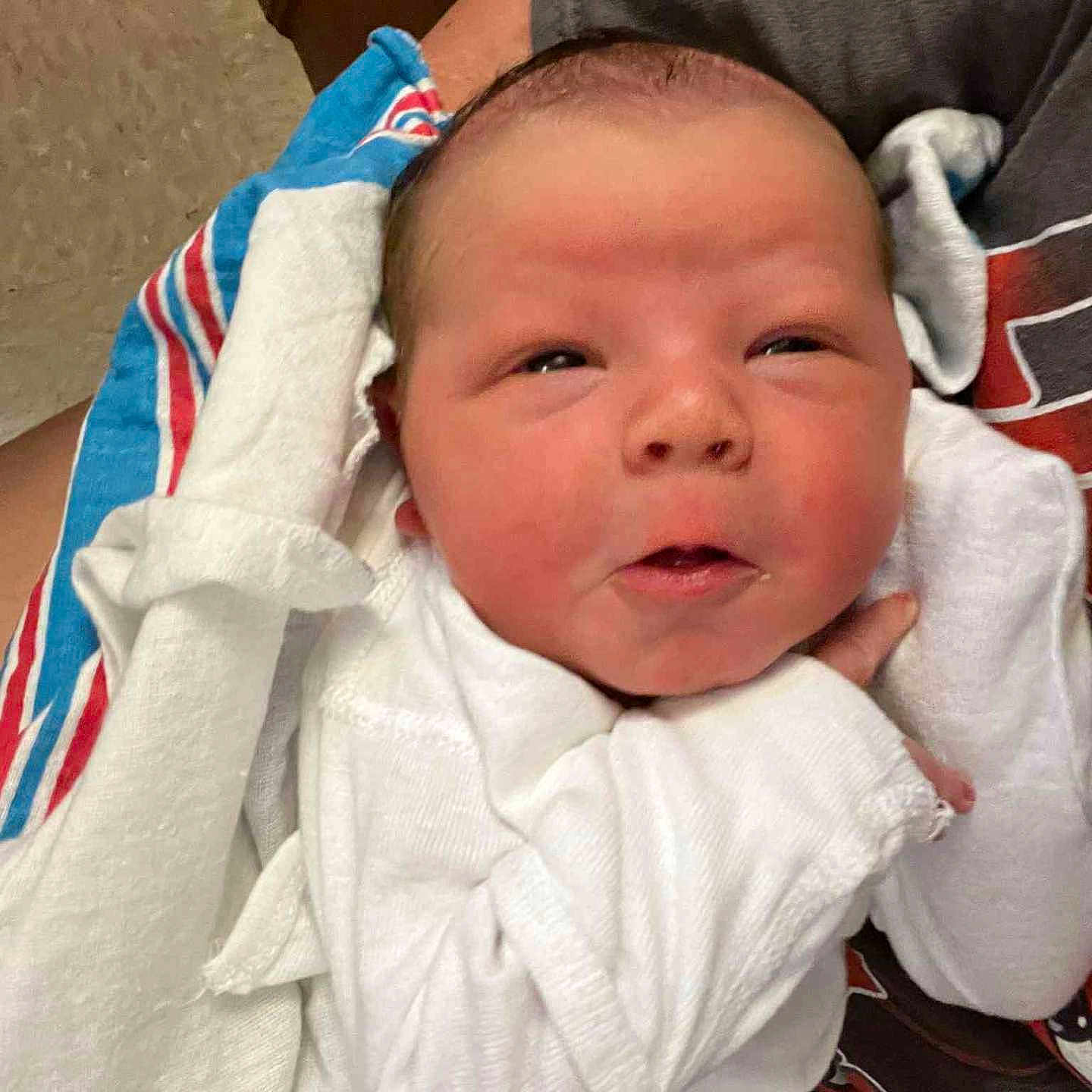 Liam is registered to the contest to win money with this photo: baby, blanket, closeup, comfort, cradling, cute, expression, face, hand, head, human, indoor, infant, newborn, person, resting, skin, sleepwear, toddler, white_clothing