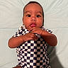 baby, infant, child, checkered_clothing, hands, face, eyes, mouth, skin, lying_down, soft_surface, blue_background, cute, portrait, one_person, indoors, young_child, expression, curious, casual
