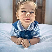 Mylan a rejoint le concours — aidez-le/la à gagner de superbes lots ! baby, child, smiling, portrait, indoor, bed, white_bedspread, striped_clothing, blue_clothing, hands, face, head, hair, happy, cute, infant, young_child, wooden_headboard, soft_texture, lying_down