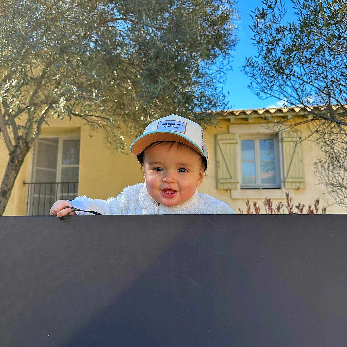 Sacha participe au concours pour gagner de l'argent avec cette photo : architecture, baby, baseballcap, building, cap, city, clothing, face, grass, hat, head, outdoors, person, photography, plant, portrait, road, shelter, street, tree