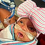 baby, blanket, bow_hat, care, close_up, cute, eyes, face, healthcare, hospital, infant, lying_down, medical_equipment, mouth, newborn, oxygen_tube, person, skin, striped, wrapped