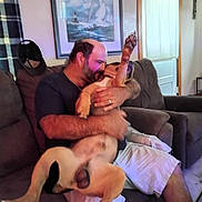 Bandit joined the competition — help win amazing prizes! affection, balding, beard, casual_clothing, couch, curtains, dog, home, indoor, living_room, love, man, painting, paw, person, pet, seated, shorts, smile, window