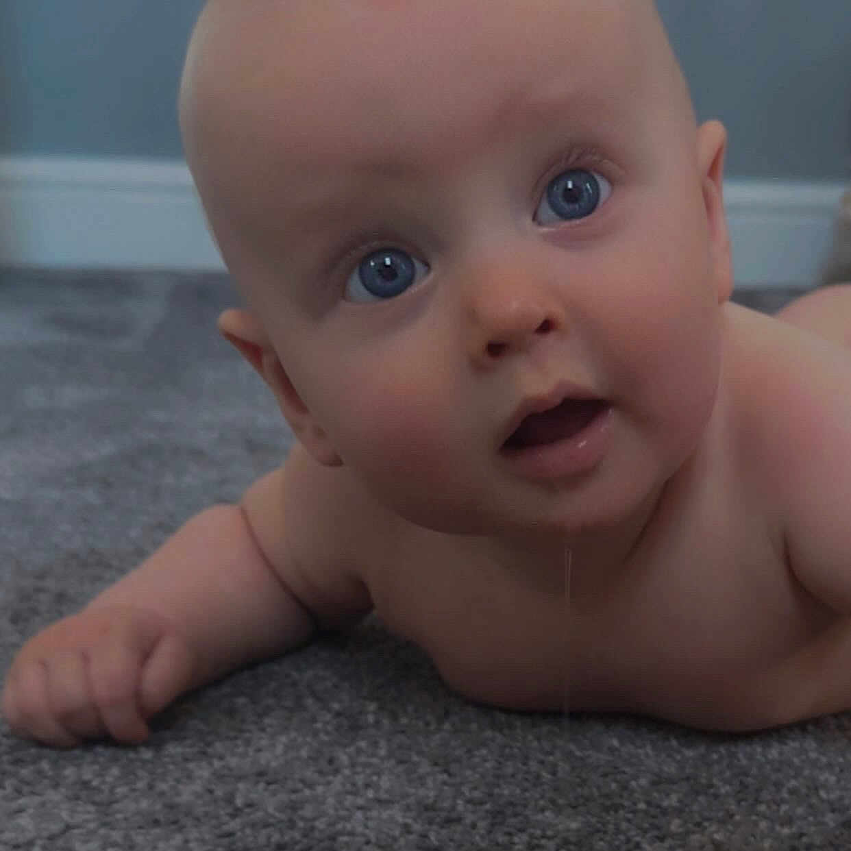 Louie is registered to the contest to win money with this photo: baby, blue_eyes, carpet, child, closeup, curious, cute, drool, expression, floor, hand, head, indoor, infant, naked, person, portrait, skin, toddler, young