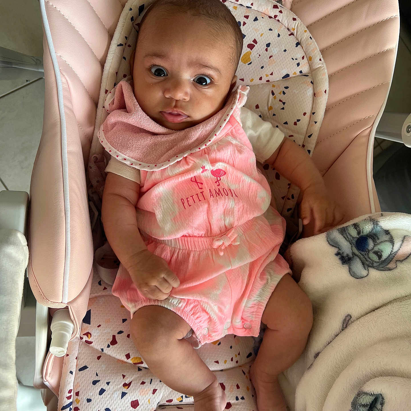 Thaïssia a rejoint le concours — aidez-le/la à gagner de superbes lots ! baby, baby_chair, bib, blanket, child, comfort, cute, expression, eyes, fabric, face, floor_tiles, foot, hand, indoor, infant, person, pink_clothing, seated, soft_toy