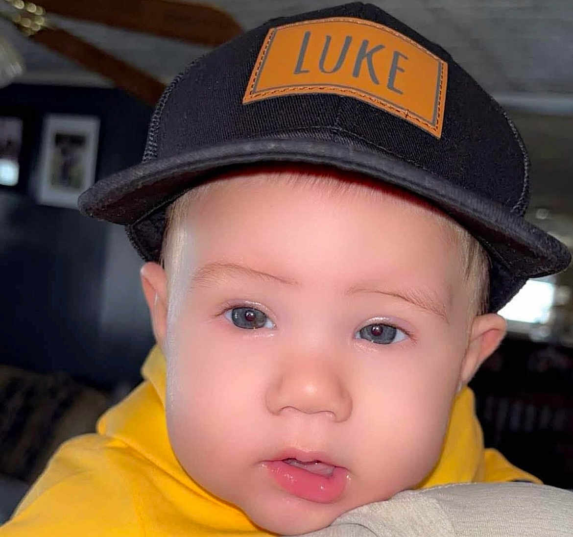Luke joined the competition — help win amazing prizes! baby, child, face, cap, hat, yellow_hoodie, indoor, portrait, close_up, cute, person, clothing, headwear, young_child, eyes, skin, expression, casual, infant, indoors