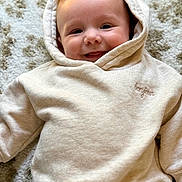 Mattéo a rejoint le concours — aidez-le/la à gagner de superbes lots ! baby, hoodie, smile, face, child, happy, infant, clothing, texture, rug, young_child, cute, portrait, casual_wear, indoor, headwear, light_beige, soft, baby_fashion, cozy