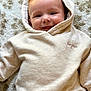 baby, hoodie, smile, face, child, happy, infant, clothing, texture, rug, young_child, cute, portrait, casual_wear, indoor, headwear, light_beige, soft, baby_fashion, cozy