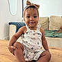 toddler, child, baby, table, romper, headband, bow, smile, face, living_room, couch, furniture, wood, curly_hair, skin, indoors, cute, sitting, person, happy