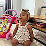 Alina participe au concours pour gagner de l'argent avec cette photo : toddler, child, baby, headband, romper, toy_walker, carpet, table, book, indoor, curtains, window, floor, furniture, person, sitting, playing, cute, curious, expression