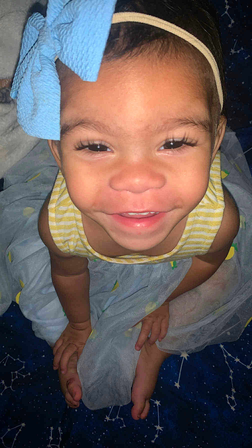 Lai Onna joined the competition — help win amazing prizes! baby, barefoot, blanket, blue_skirt, bow, child, closeup, constellation_pattern, cute, face, feet, hands, happy, headband, indoor, person, portrait, smiling, toddler, yellow_striped_top