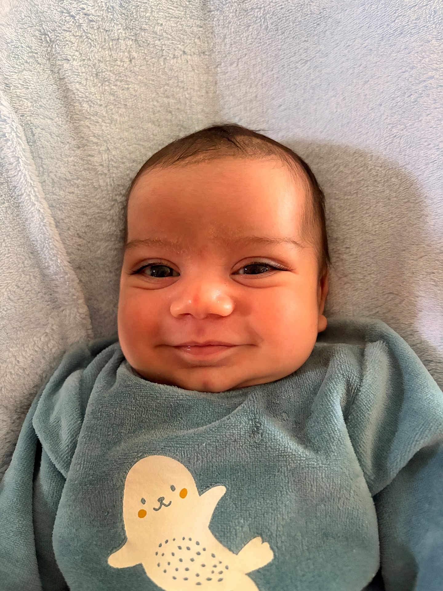Egor participe au concours pour gagner de l'argent avec cette photo : baby, smile, infant, toddler, face, cheeks, eyes, onesie, seal_print, blanket, towel, soft_texture, clothing, portrait, closeup, lying_down, skin, happy, cute, indoor