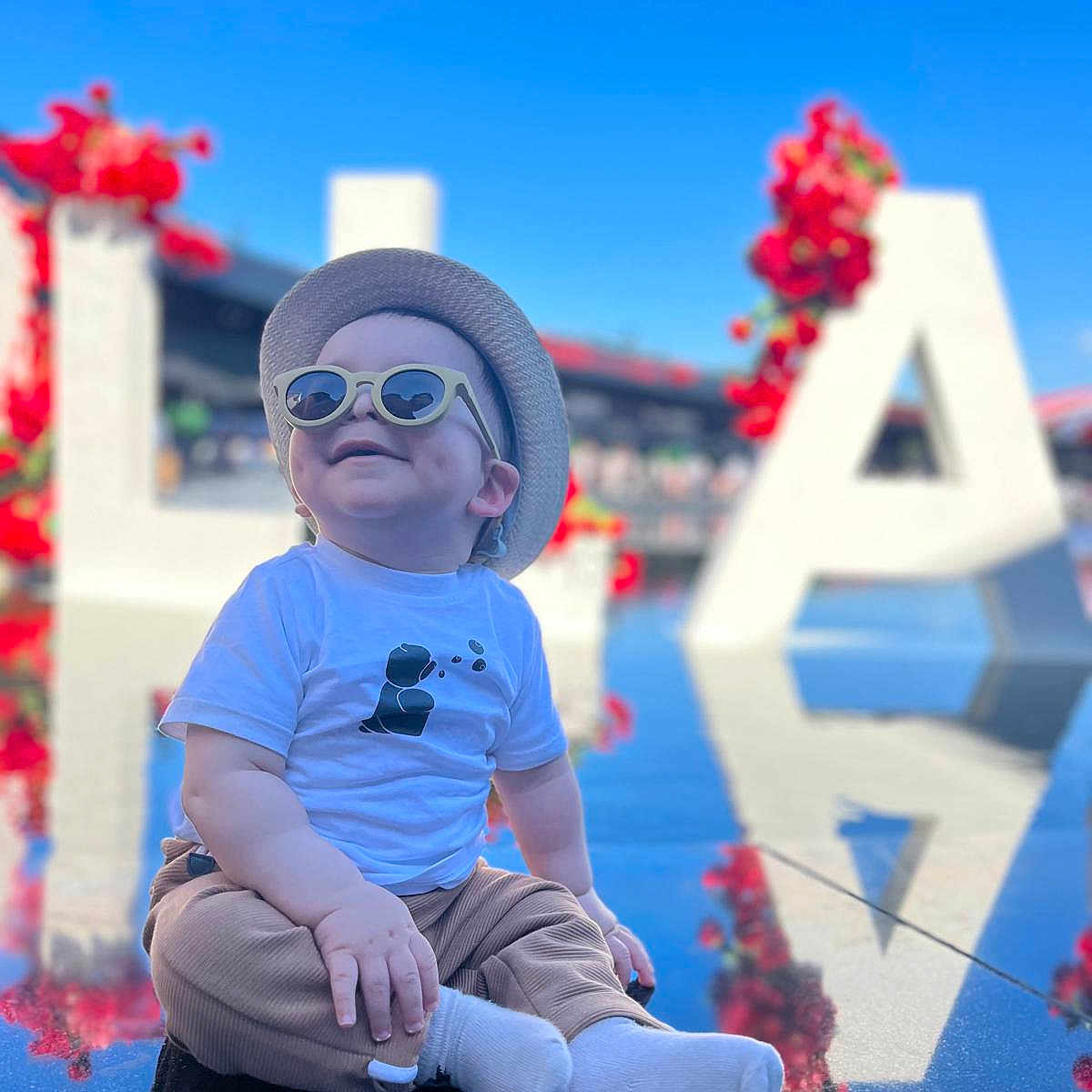 Ishak a rejoint le concours — aidez-le/la à gagner de superbes lots ! baby, blue_sky, casual, child, cute, dimple, flower, hat, large_letter, letter, outdoor, pants, portrait, red_flower, reflection, smile, socks, sunglasses, sunny, tshirt