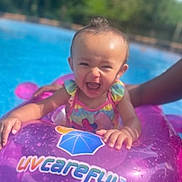 Gracelynn is registered to the contest to win money with this photo: baby, child, pool, float, swimming, water, smile, happy, outdoor, summer, sunny, purple, splash, fun, person, infant, play, toy, hand, clothing