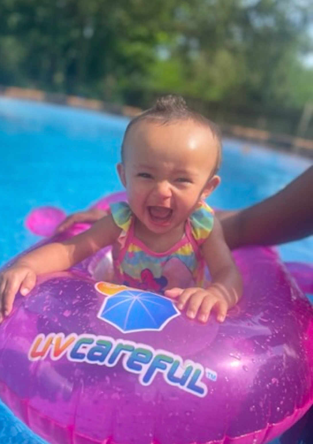 Gracelynn is registered to the contest to win money with this photo: baby, child, pool, float, swimming, water, smile, happy, outdoor, summer, sunny, purple, splash, fun, person, infant, play, toy, hand, clothing