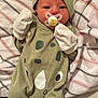 baby, newborn, pacifier, mittens, hat, green_outfit, rhino_design, striped_blanket, lying_down, infant, sleepwear, cute, small, child, person, cozy, soft, indoor, resting, wearing