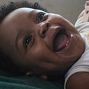 Angel joined the competition — help win amazing prizes! baby, smiling, face, child, infant, happy, curly_hair, mouth_open, teeth, skin, person, closeup, lying_down, cute, expression, joyful, indoors, soft_light, clothing, fabric