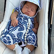 Vanessa joined the competition — help win amazing prizes! baby, sleeping, stroller, dress, hat, white_socks, pacifier, bead_chain, cushion, infant, peaceful, child, outdoor, blue_and_white, patterned_clothing, hand, footwear, closeup, cute, resting