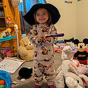 Brynlee is registered to the contest to win money with this photo: toddler, child, pajamas, wizard_hat, wand, smiling, toy_room, stuffed_animals, plush_bunny, mickey_mouse, carpet, coloring_book, toy_balls, furniture, curtains, wall_decor, happy, indoor, playful, person