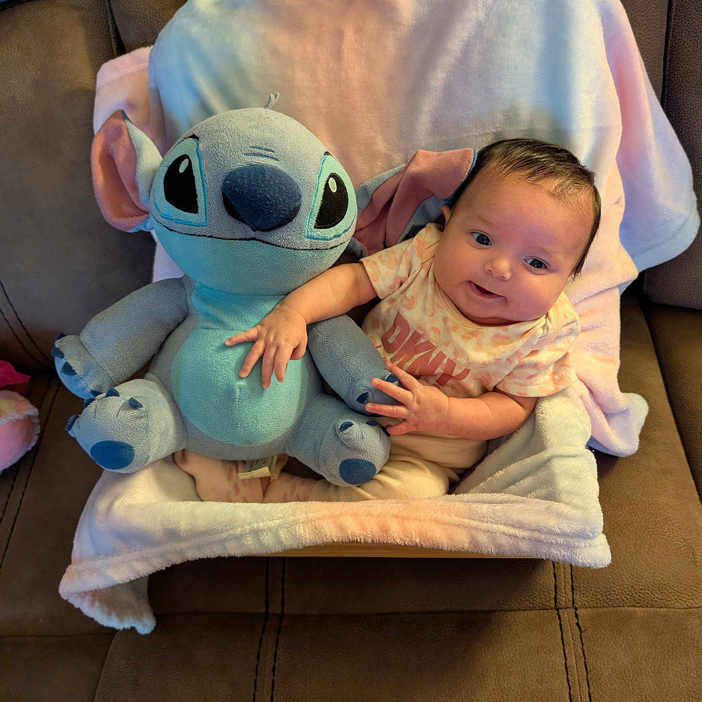Aliyah joined the competition — help win amazing prizes! baby, plush_toy, stitch, blanket, couch, smiling, infant, soft_toy, child, cute, happy, indoors, seated, person, cozy, small_child, toddler, fabric, hand, portrait