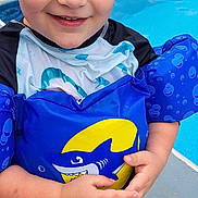 Colton joined the competition — help win amazing prizes! child, boy, pool, floatation_device, swimwear, water_shoes, shark, smiling, wet_hair, outdoor, summer, blue, red, splash, playful, happy, person, swimming, fun, water