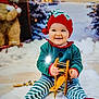 baby, child, toy, wooden_toy, airplane_toy, elf_costume, striped_pants, red_hat, smiling, indoor, holiday_theme, winter_background, teddy_bear, snow, festive, cute, playful, sitting, portrait, happy