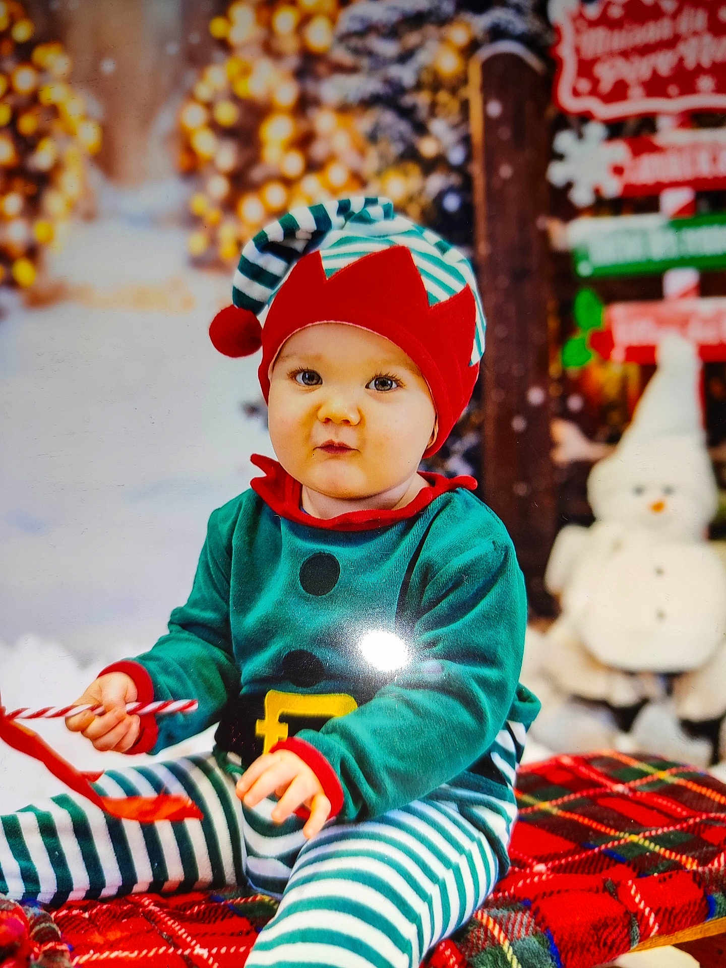 Eden a rejoint le concours — aidez-le/la à gagner de superbes lots ! toddler, child, elf_costume, holiday, christmas, candy_cane, plaid_blanket, festive, cute, smiling, striped_pants, red_hat, decorations, snowman, indoors, portrait, holiday_lights, seasonal, baby, happy