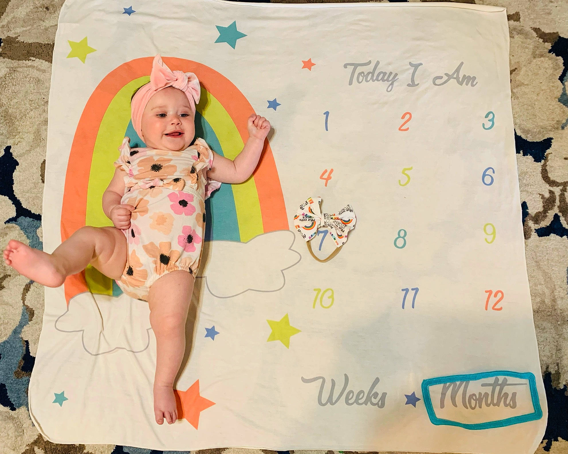 Elianna is registered to the contest to win money with this photo: art, baby, baby_toddler_clothing, barefoot, child, event, font, foot, happy, headwear, linens, pattern, people_in_nature, person, pink, room, sitting, smile, t_shirt, textile