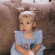 Madelyn is registered to the contest to win money with this photo: blonde_hair, blue_dress, casual, child, couch, curious_expression, cute, flash, furniture, hair_buns, holding_object, home, indoor, person, portrait, red_eye, sitting, toddler, window, young_child
