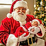 Malone is registered to the contest to win money with this photo: baby, santa_claus, christmas_tree, holiday, festive, red_clothing, white_beard, glasses, sleeping, hat, gloves, chair, indoor, decorations, belt, smile, portrait, seasonal, celebration, warmth