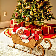 Malone joined the competition — help win amazing prizes! baby, christmas, santa_claus, sleigh, sleeping, holiday, decorations, presents, tree, ornaments, red_clothing, wooden, indoor, festive, gift_wrap, cozy, seasonal, holiday_spirit, cute, infant