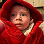 apparel, baby, candid, child, closeup, cozy, curious, cute, expression, face, hood, indoor, indoors, infant, person, portrait, red_robe, soft_light, warm_clothing, young_child
