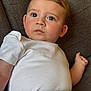 baby, blue_eyes, casual_clothing, cheeks, child, closeup, couch, curious_expression, face, furniture, green_pants, hair, indoors, infant, laying_down, person, portrait, skin, white_shirt, young