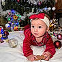 baby, child, christmas, holiday, festive, red_clothing, headband, bow, gingerbread_man, ornament, christmas_tree, lights, decorations, white_blanket, indoor, cute, holiday_spirit, celebration, toy, smiling