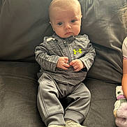 Thomas joined the competition — help win amazing prizes! baby, infant, child, sitting, couch, gray_clothing, socks, indoor, portrait, young_child, zip_up_jacket, neon_logo, cute, small_hands, looking_at_camera, soft_lighting, casual_clothing, relaxed, home, cozy