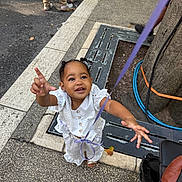 Elyjah a rejoint le concours — aidez-le/la à gagner de superbes lots ! child, toddler, smiling, reaching, ribbon, purple_ribbon, white_outfit, street, pavement, stroller, tree, tree_grate, crowd, shoes, legs, happy, urban, portrait, sandals, public_event