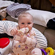 Liya participe au concours pour gagner de l'argent avec cette photo : baby, infant, pajamas, sock, chewing, cushion, toy, blanket, indoor, cute, child, person, face, blue_eyes, plush, comfort, smiling, hand, seated, soft