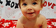 Jasper Lynn Thomas is registered to the contest to win money with this photo: baby, child, smiling, toy, red_blanket, snowflake_pattern, love_message, xoxo, lipstick_kiss, happy, face, sitting, indoor, diaper, cute, playful, background_text, infant, skin, portrait