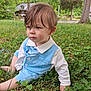 toddler, child, grass, outdoor, blue_outfit, white_shirt, sitting, portrait, greenery, nature, serious_expression, young_child, casual_pose, daylight, clothing, cute, person, face, hair, yard