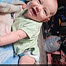 Echo is registered to the contest to win money with this photo: baby, infant, smiling, diaper, green_shirt, blanket, floor, toy, pink_toy_car, clutter, indoor, child, cute, happy, lying_down, attempting_to_roll, person, face, playful, text_overlay