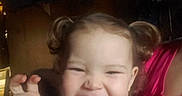 Isabella is registered to the contest to win money with this photo: baby, blurred_background, child, clothing, cute, expression, face, hand, happy, indoor, light, person, person_holding_child, pigtails, pink_shirt, portrait, purple_shirt, smile, toddler, young