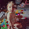 child, toy, carpet, star_effect, sunlight, playroom, indoor, colorful, pattern, girl, sitting, floor, cute, playtime, soft_toys, casual_clothing, daylight, expression, young_child, home