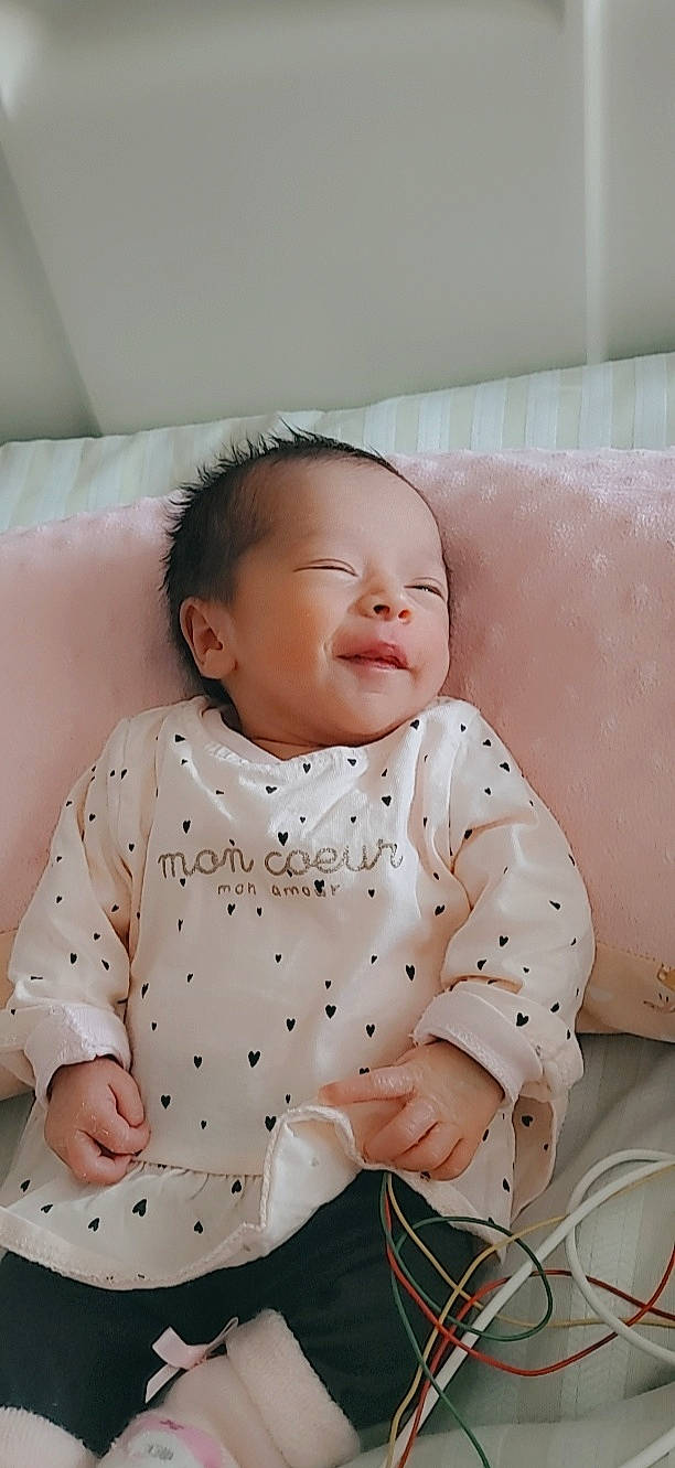 June participe au concours pour gagner de l'argent avec cette photo : baby, baby_safety, baby_sleeping, baby_toddler_clothing, cheek, child, chin, comfort, dress, happy, head, linens, mouth, person, pink, product, skin, sleeve, smile, toddler